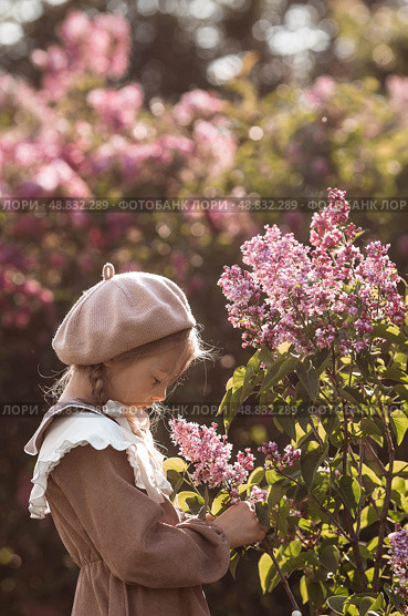 Vintage women's accessories and retro-style clothing. A small, beautiful girl with bows in her hair, in a beige dress and a beret outdoors. Стоковое фото, фотограф Photojuli / Фотобанк Лори