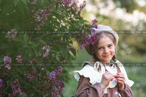 Vintage women's accessories and retro-style clothing. A small, beautiful girl with bows in her hair, in a beige dress and a beret outdoors. Стоковое фото, фотограф Photojuli / Фотобанк Лори