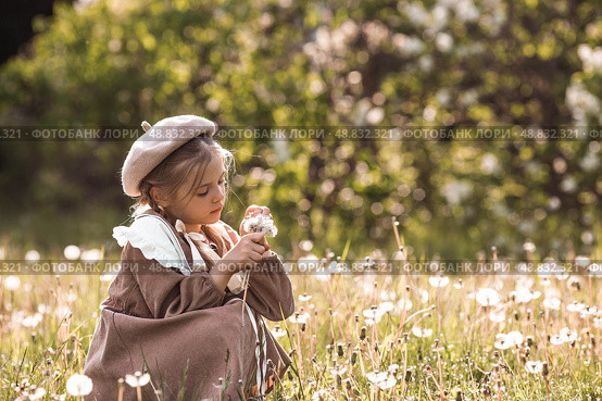 Vintage women's accessories and retro-style clothing. A small, beautiful girl with bows in her hair, in a beige dress and a beret outdoors. Стоковое фото, фотограф Photojuli / Фотобанк Лори