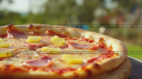 Вкусная пицца с ветчиной и ананасом (Гавайская) на открытом воздухе / Tasty ham and pineapple pizza on outdoor table. Стоковое AI-видео, аниматор DeFusum / Фотобанк Лори