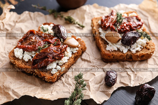 Вкусные брускетты с сыром, вялеными томатами и финиками, крупным планом. Стоковое фото, фотограф Pixel_shot / Фотобанк Лори