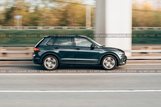 Volkswagen Tiguan in the motion on the highway. VW SUV car drive on asphalt city road. Unacceptable speeding concept. Редакционное фото, фотограф Константин Григорьев / Фотобанк Лори