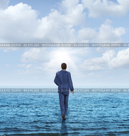 Walk on water with a businessman walking on the surface of an ocean as a business concept of confidence and courage to take on an impossible challenge and achieve success with the power of belief. Стоковое фото, агентство Ingram Publishing / Фотобанк Лори