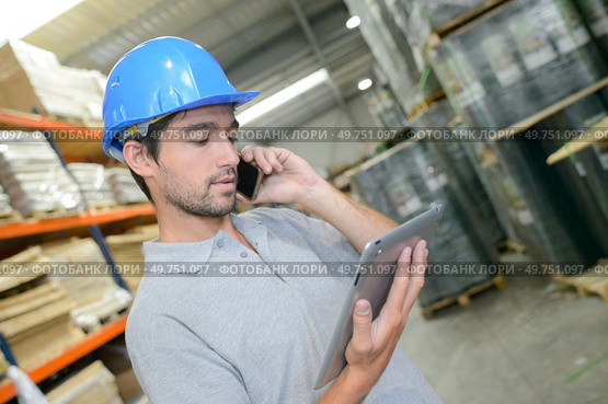 Warehouse worker on phone holding tablet. Стоковое фото, агентство Ingram Publishing / Фотобанк Лори