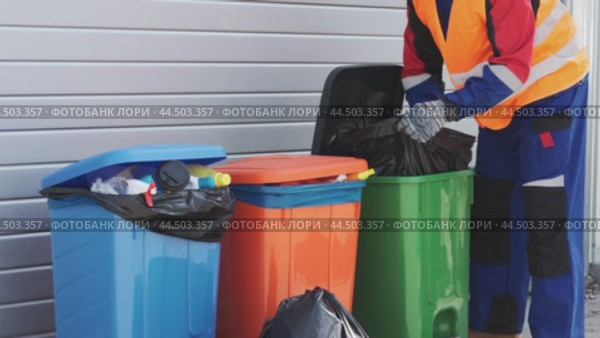 Waste management worker sorts recyclable materials in a busy urban area during daylight hours. Стоковое видео, видеограф Сергей Толмачёв / Фотобанк Лори