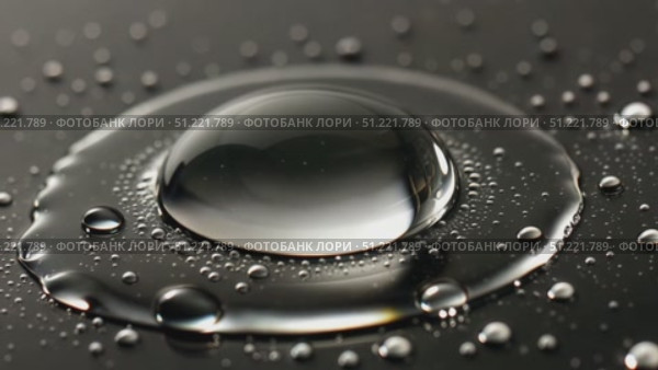 Water droplet clinging reflectively to dark surface, rimmed by liquid ring, tiny satellite droplets surrounding, forming minimalist abstract pattern. Стоковое AI-видео, аниматор Юрий Поздников / Фотобанк Лори