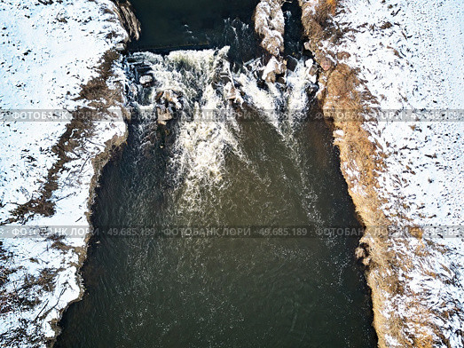 Waterfall on winter creek. Snow on frozen riverbanks. Top Aerial View Of River Cascade. Stream water flowing between rocks. Europe. Стоковое фото, агентство Ingram Publishing / Фотобанк Лори