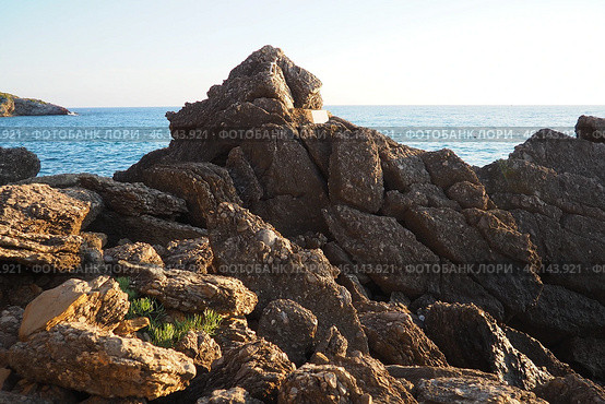 Waves gently crash against the rugged rocks while the sun sets over the horizon. Experience the serene beauty of this coastal location filled with natural wonders. Canj, Montenegro, Adriatic sea (2024 год). Стоковое фото, фотограф Юлия Петровская / Фотобанк Лори