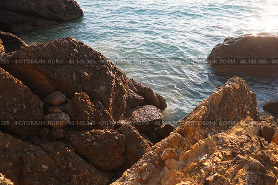Waves gently crash against the rugged rocks while the sun sets over the horizon. Experience the serene beauty of this coastal location filled with natural wonders. Canj, Montenegro, Adriatic sea (2024 год). Стоковое фото, фотограф Юлия Петровская / Фотобанк Лори