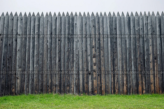 Weathered wooden palisade protecting verdant grassland, marking territorial boundary in expansive russian countryside terrain. Стоковое фото, фотограф Mikhail Davidovich / Фотобанк Лори