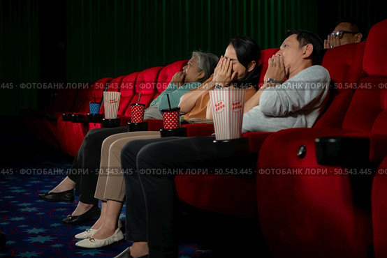 When watching scary ghost movies in theaters, moviegoers appear terrified. Стоковое фото, агентство Ingram Publishing / Фотобанк Лори