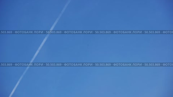 White airplane flying high in clear blue sky leaving contrail. Стоковое видео, видеограф Mikhail Davidovich / Фотобанк Лори
