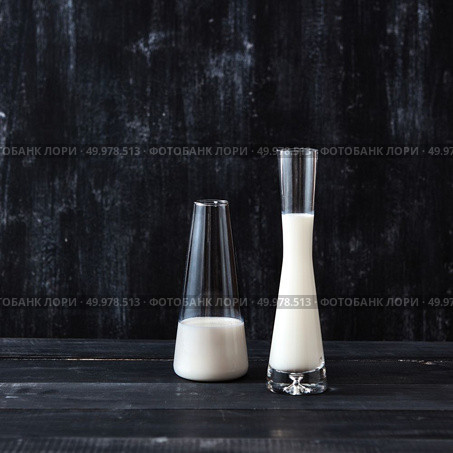 White milk in a glasses on a black background with place for text. Milk saving technology.. Two glasses with milk on a wooden dark table on a black. Natural organic dairy product. Стоковое фото, агентство Ingram Publishing / Фотобанк Лори