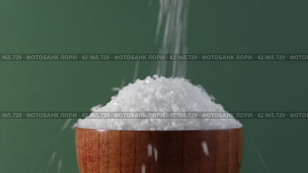 White table salt granules falling into a pile. Wood bowl. Gray color studio background. Condiment particles dropping. Clean cosmetic bath salt pouring footage. Closeup of grained sea salt pieces hill. Стоковое видео, видеограф Марина Демидюк / Фотобанк Лори