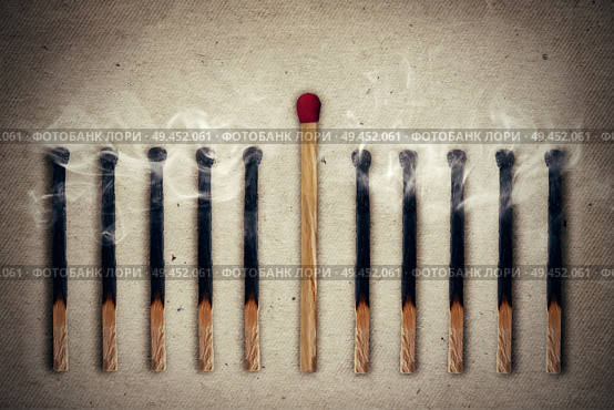 Whole, unused match standing middle a row of extinguished, burnt matches. Standing out from the crowd, leadership concept. Стоковое фото, агентство Ingram Publishing / Фотобанк Лори