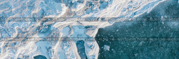 Winter aerial photograph of the icy coast and ice floes in sea water. Top view of the freezing sea. Northern nature. Frosty winter weather. Cold arctic climate. Beautiful wide panoramic background. Стоковое фото, фотограф Андрей Степанов / Фотобанк Лори