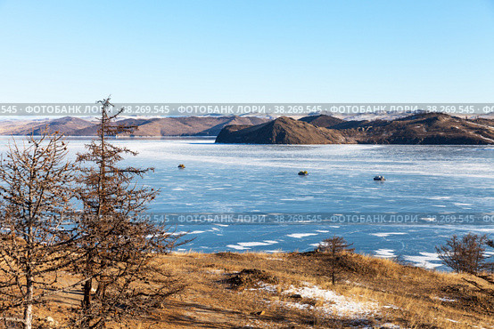 Winter Baikal Lake. View from coastal hills to frozen Kurkut Bay on cold January day. All-terrain vehicles on hovercraft Hivus transport tourists to Olkhon Island. Natural background. Concept of ice travels. Стоковое фото, фотограф Виктория Катьянова / Фотобанк Лори