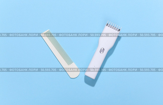 Wireless hair clipper and comb on blue bright background. Top view. Стоковое фото, агентство Ingram Publishing / Фотобанк Лори