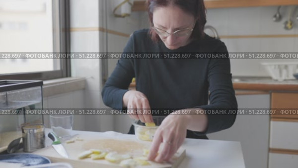 Woman arranging sliced potatoes in glass bowl in kitchen. Стоковое видео, видеограф Константин Шишкин / Фотобанк Лори