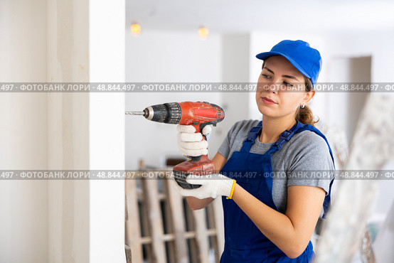 Woman builder using drill to bore hole in wall. Стоковое фото, фотограф Яков Филимонов / Фотобанк Лори