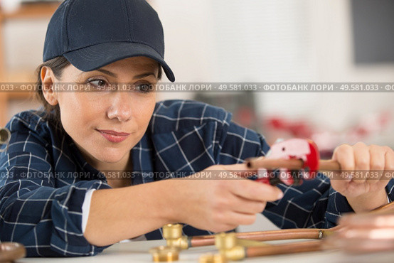 woman cutting cooper pipes. Стоковое фото, агентство Ingram Publishing / Фотобанк Лори