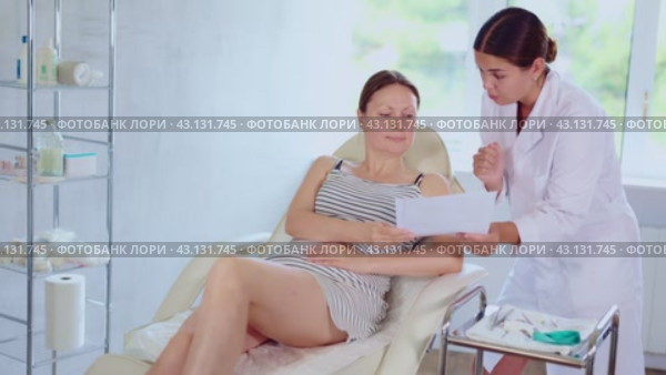 Woman doctor give patient medical documents for review before carrying out cosmetic procedure. Стоковое видео, видеограф Яков Филимонов / Фотобанк Лори