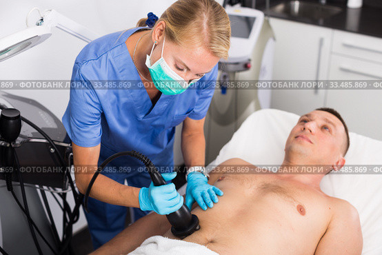 Woman doctor is doing vacuum massage procedure on belly of adult client. Стоковое фото, фотограф Яков Филимонов / Фотобанк Лори
