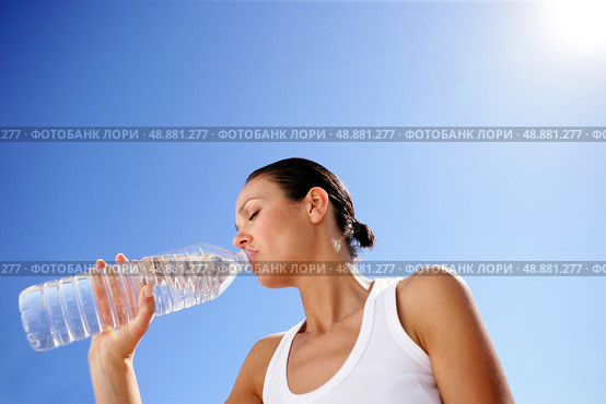 Woman drinking a bottle of water against a blue sky. Стоковое фото, агентство Ingram Publishing / Фотобанк Лори