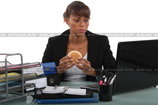 Woman eating a hamburger at her desk. Стоковое фото, агентство Ingram Publishing / Фотобанк Лори