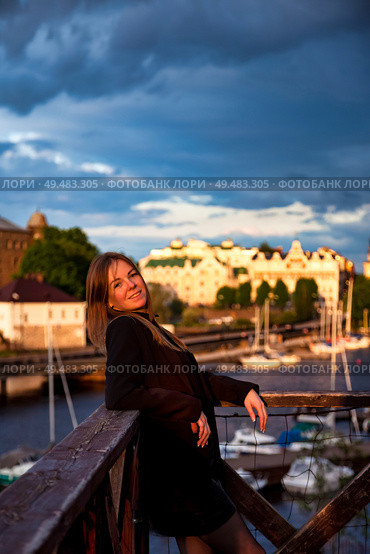 Woman Enjoying a Sunset by the Waterfront in a Charming Coastal Town. Стоковое фото, фотограф Aleksandr Golubev / Фотобанк Лори