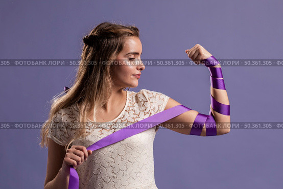 woman flexing her arm with ribbon as sign empowerment. Стоковое фото, агентство Ingram Publishing / Фотобанк Лори