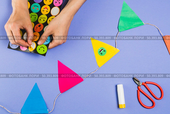 woman hand making bunting with emoji stickers colored background. Стоковое фото, агентство Ingram Publishing / Фотобанк Лори