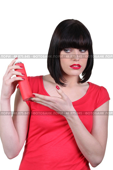 Woman in red looking warily at an aerosol. Стоковое фото, агентство Ingram Publishing / Фотобанк Лори
