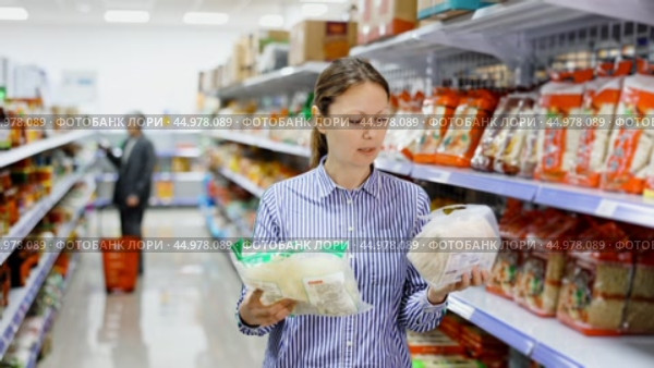 Woman in supermarket buys daily groceries, pasta Chinese noodles. Стоковое видео, видеограф Яков Филимонов / Фотобанк Лори