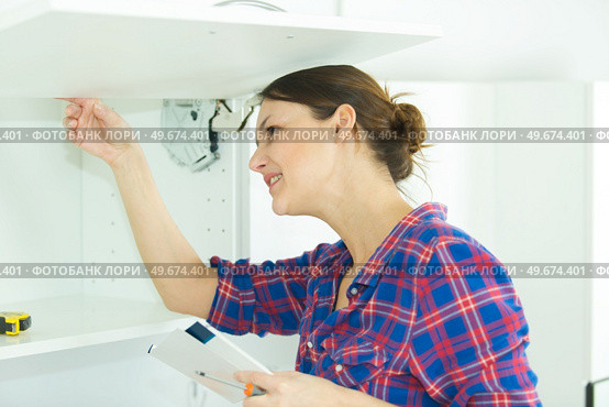 woman inspecting her installed cupboard. Стоковое фото, агентство Ingram Publishing / Фотобанк Лори