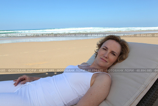 Woman lying on sun lounger. Стоковое фото, агентство Ingram Publishing / Фотобанк Лори