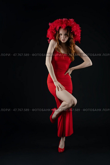 Woman posing with flair and emotion in a striking red dress and vibrant headpiece in a studio setting. Стоковое фото, фотограф Гурьянов Андрей / Фотобанк Лори
