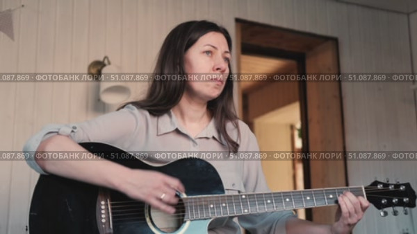 Woman Practicing Guitar in Cozy Room at Home. Strumming black acoustic guitar. Female learning to play music. Person hand on a guitar neck. Guitarist working on melody, performance, practice indoors. Стоковое видео, видеограф Марина Демидюк / Фотобанк Лори