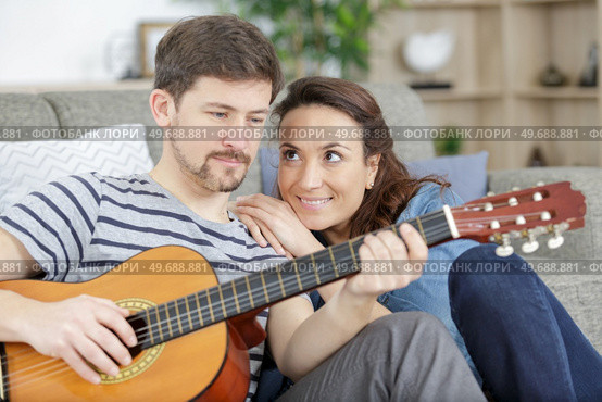 woman proudly watching her partner play the guitar. Стоковое фото, агентство Ingram Publishing / Фотобанк Лори