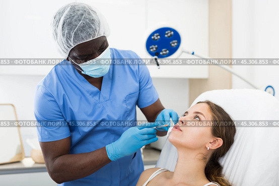 Woman receiving injections for lip augmentation at cosmetology clinic. Стоковое фото, фотограф Яков Филимонов / Фотобанк Лори