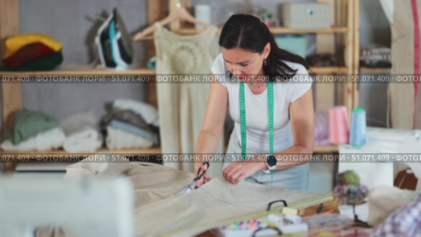 Woman seamstress cutting fabric in sewing workshop. Стоковое видео, видеограф Яков Филимонов / Фотобанк Лори