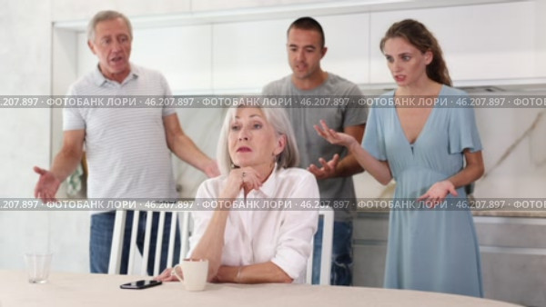 Woman sits at table in kitchen and pretends not to understand her family. Стоковое видео, видеограф Яков Филимонов / Фотобанк Лори