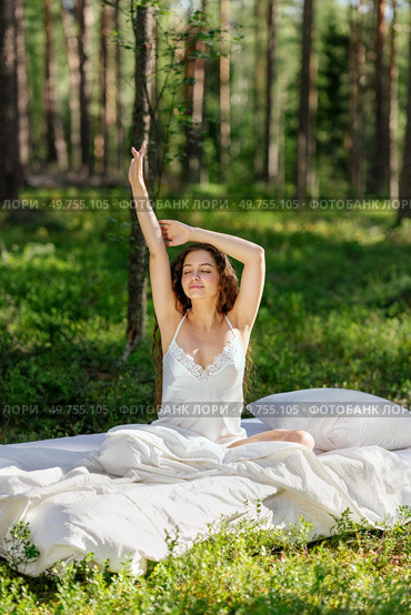 Woman sleeps on a mattress in the summer forest. Girl wakes up in a summer forest. Стоковое фото, агентство Ingram Publishing / Фотобанк Лори