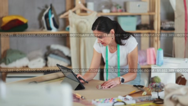 Woman tailor uses tablet when creating drawing of future product. Стоковое видео, видеограф Яков Филимонов / Фотобанк Лори
