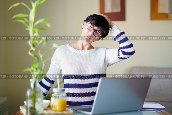 Woman teleworking from home with her laptop taking a stretch break.. Middle-aged woman teleworking taking a stretch break. Стоковое фото, агентство Ingram Publishing / Фотобанк Лори