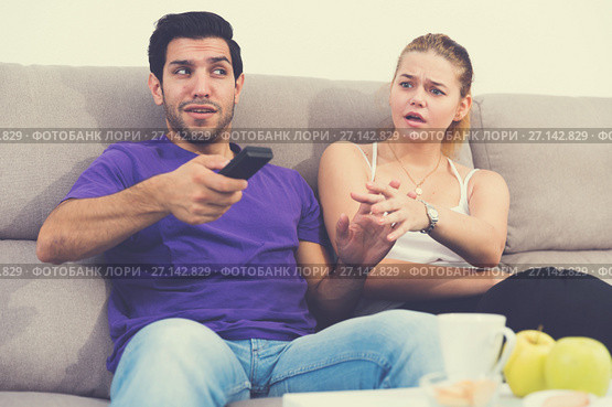 Woman trying to take away TV remote from boyfriend. Стоковое фото, фотограф Яков Филимонов / Фотобанк Лори