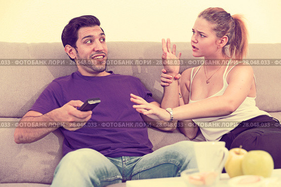 Woman trying to take away TV remote from boyfriend. Стоковое фото, фотограф Яков Филимонов / Фотобанк Лори