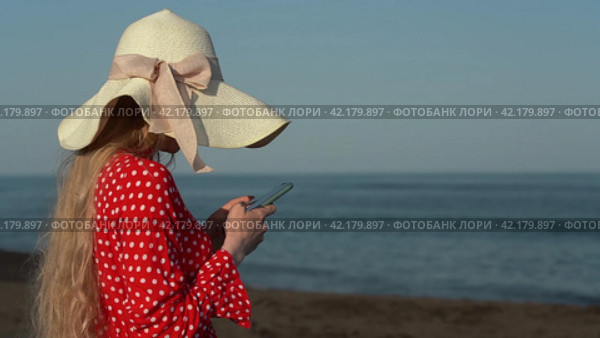 Woman using smartphone, reading and typing text messaging on beach on background of waves of sea. Стоковое видео, видеограф А. А. Пирагис / Фотобанк Лори