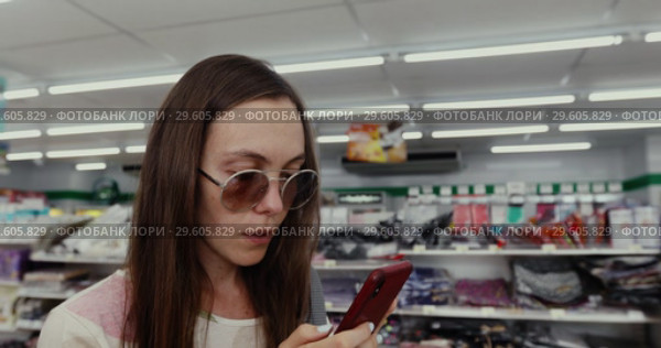 Woman Using the Phone in the Store. Стоковое видео, видеограф Ekaterina Demidova / Фотобанк Лори