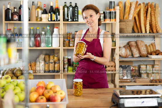 Woman vendor selling canned olives in grocery department of supermarket. Стоковое фото, фотограф Яков Филимонов / Фотобанк Лори